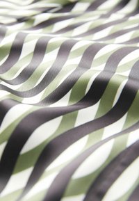 Textil mit einem wellenförmigen Muster in Dunkelgrün, Hellgrün und Weiß. Glatte Textur mit glänzender Oberfläche.