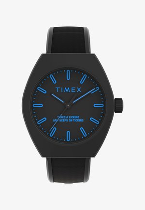 Černé hodinky Timex s hexagonálním pouzdrem, modrými indexy a ručičkami. Mají texturovaný černý gumový pásek a modrý text na ciferníku.