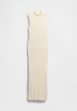 Long, sleeveless, cream-colored dress with a high mock neck. Ribbed texture, form-fitting design, and floor-length silhouette.