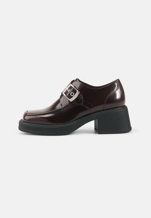 Burgundy patent leather shoes with a square toe, block heel, and a side buckle detail. Features a smooth finish and soft texture.