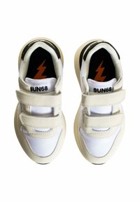 Sneaker bianche con dettagli beige, cinturini in velcro e tacco nero. Presentano una superficie testurizzata e un logo a forma di saetta sulla soletta.