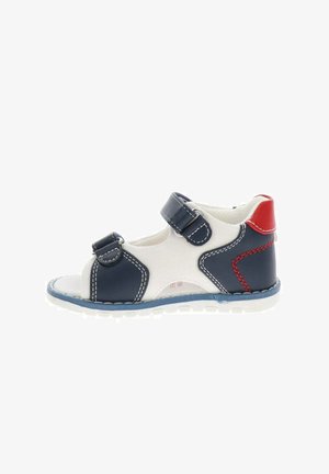 Sandale enfant à bout ouvert avec brides bleu marine, base en tissu blanc, détail rouge au talon et fermetures Velcro ajustables sur une semelle blanche.