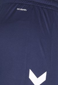 Marine treningsshorts laget av glatt stoff. Har en hvit "BEECOOL"-logo og et hvitt chevronmønster nær bunnen. Elastisk midjebånd.