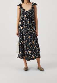 Svart blommig klänning med volangärmar, som har flerfärgade blommönster, en åtsittande midja och en flödande knälång kjol.