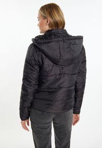Jachetă puf din neopren neagră, cu glugă, textură matlasată și manșete elastice, văzută din spate. Materialul are un finisaj lucios și un design ajustat.