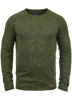 Grön tröja i strukturerad stickad tyg, med rund halsringning, långa ärmar och en liten brun logotyp-patch på den nedre framdelen.