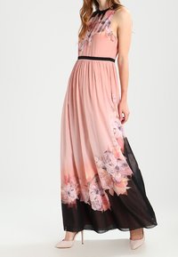 Maxikleid aus softpinkem Stoff mit floralen Mustern, schwarzem Taillenbund und transparentem schwarzen Saum. Hat einen ärmellosen Schnitt und eine fließende Silhouette.