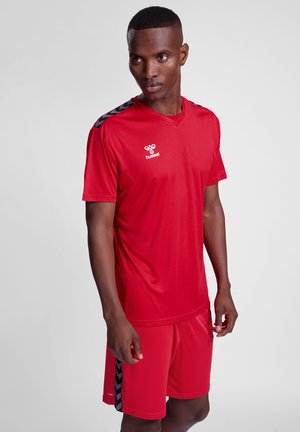 Rødt atletiksæt med en kortærmet skjorte med sorte detaljer og matchende shorts, lavet af let og åndbart materiale.