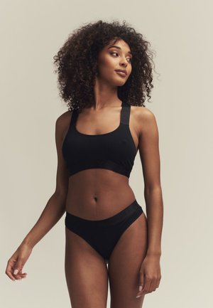 Schwarzer Sport-BH mit breiten Trägern und passenden hochgeschnittenen Bikini-Höschen. Glattes Material mit dezentem Branding am Bund. Flache Nähte.