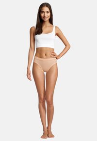 Top corto bianco in cotone abbinato a culotte nude a vita alta. Entrambi i capi hanno una texture liscia e un design semplice e contemporaneo.
