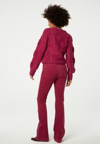 Fuchsia gebreide trui met gestructureerde hartpatronen, gecombineerd met bijpassende flared corduroy broeken. Beide items hebben een zachte, gezellige afwerking.