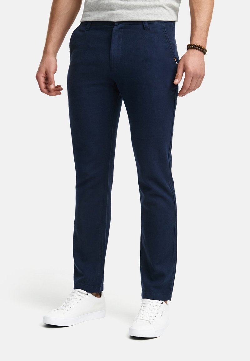Marineblauwe chino's in een slim fit, met een gestructureerde stof, voorke pocketen en minimale zijkanten. Gepaard met witte sneakers.