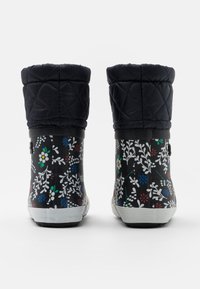 Bottes noires imperméables avec un dessus matelassé bleu marine, présentant un motif floral en rouge, bleu et blanc. Semelle et accents en caoutchouc blancs.