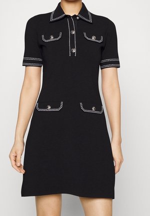 Robe noire à manches courtes avec bordure blanche cousue, col boutonné et quatre poches avant à rabat avec boutons.