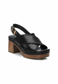 Zwarte leren slingback sandaal met gekruiste banden, open teen en een ribbelrand. Heeft een chunky houten hak en gouden hardware-accent.