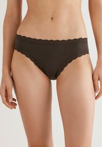 Bruine katoenen bikini met een gegolfde kanten afwerking langs de tailleband en beenopeningen; heeft een gladde textuur en een ontwerp met minimale bedekking.