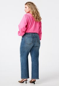 Roze gestreepte blouse met puffed sleeves, gecombineerd met hoge taille recht gesneden blauwe jeans en schoenen met hoge hakken in luipaardprint.
