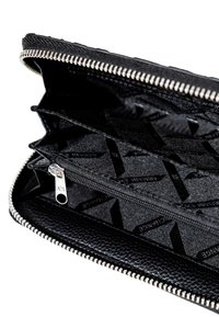 Portafoglio in pelle nera con zip aperto, che mostra più scomparti e una tasca con zip interna con un tirante in metallo argentato.