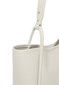 Lys grå læder tote bag med en glat tekstur, struktureret form og en slank justerbar rem. Har minimal syning og diskrete hardware detaljer.