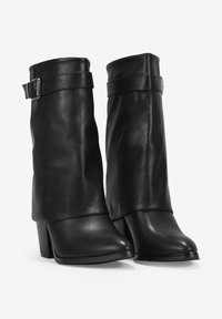 Bottines noires en cuir avec un design plissé, bout carré et talon bloc. Elles possèdent une sangle ajustable avec une boucle métallique.