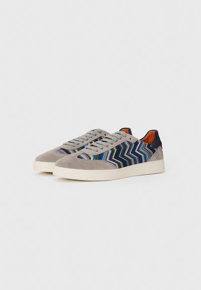 Sneakerid, millel on hall sueded välispind, sinise ja rohelise tooni sakilistest kangast elementidest, kreemjas kummitald ning hallid nöörid.