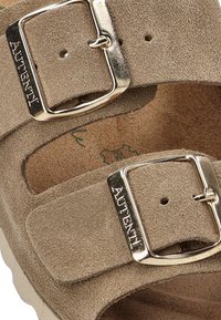 Sandalias de ante beige que cuentan con dos correas ajustables con hebillas metálicas, superficie texturizada y plantilla acolchada para mayor comodidad.