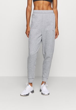 Slim-fit gray sweatpants with elastic waistband worn with white athletic shoes featuring black patterned soles.