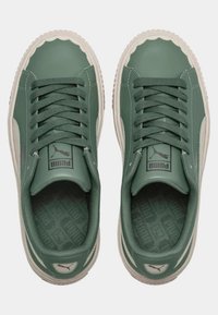 Green synthetic sneakers with rounded edges, textured beige sole, flat laces, and PUMA logo on tongue and heel.