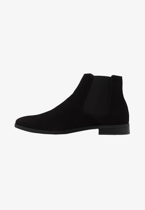 Schwarze Wildleder Chelsea-Stiefel mit elastischen seitlichen Einsätzen, einer abgerundeten Spitze und einem niedrigen, gestapelten Absatz. Sanfte Textur und minimalistisches Design.