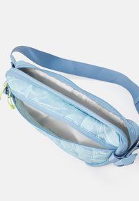 Blue fabric crossbody bag with a textured pattern, zip closure, adjustable strap, and a light-colored lining. Interior spacious and smooth.