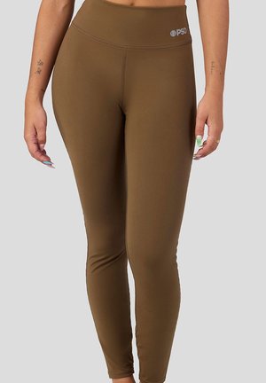 Braune Leggings mit hoher Taille aus dehnbarem Stoff, die eine glatte Textur, dezente Nähte und ein Logo am Bund aufweisen.