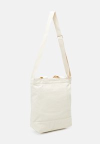 Torba na ramię z płótna w kolorze écru z regulowanym paskiem i otwarciem na górze. Posiada płaskie dno i minimalne detale szycia.