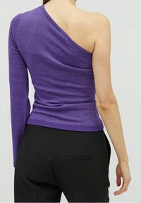 Haut violet asymétrique à épaule unique avec texture côtelée, manches longues d'un côté et coupe ajustée, associé à un pantalon noir.