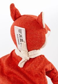 Soft fabric fox plush toy in orange and cream, featuring small pointed ears, tied scarf detail, and care label on the back.