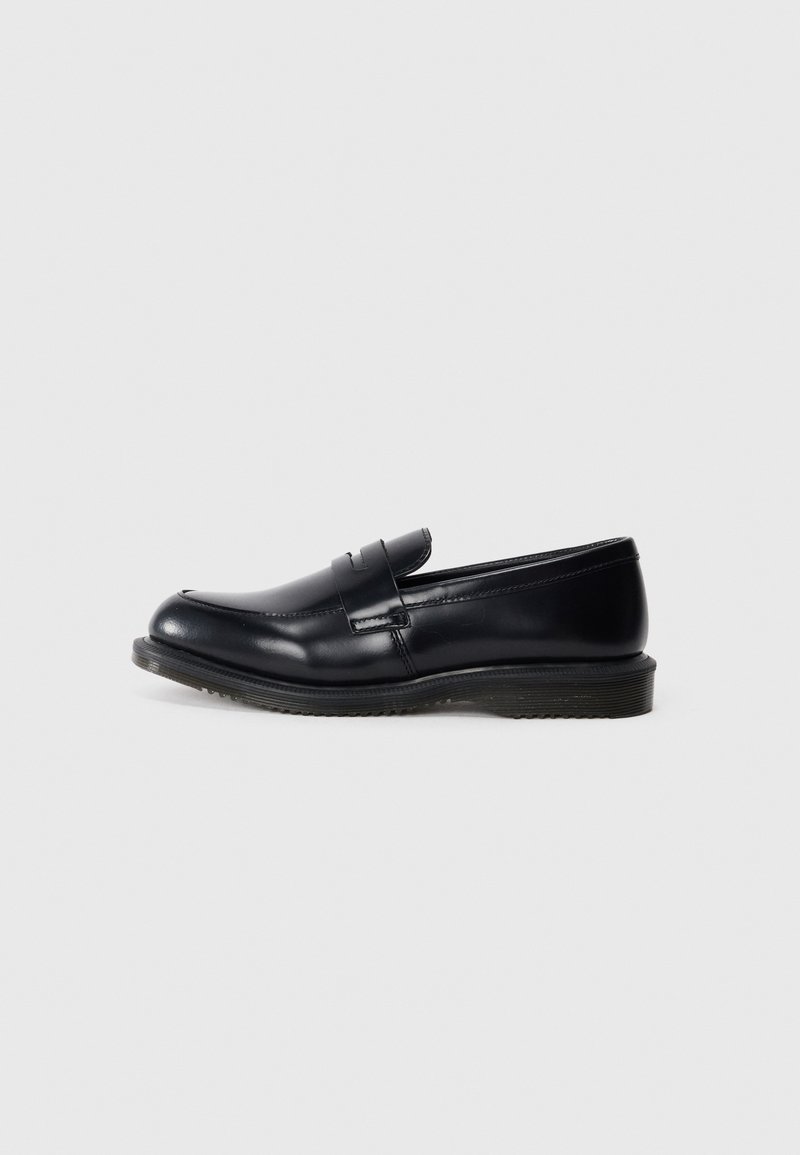 Mocassin penny en cuir noir avec talon bas et finition lisse, présenté en profil latéral sur un fond gris clair uni.