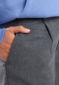 Grey tailored trousers with a smooth texture, featuring side pockets and a fitted waist. A light blue sweatshirt is partially visible above.