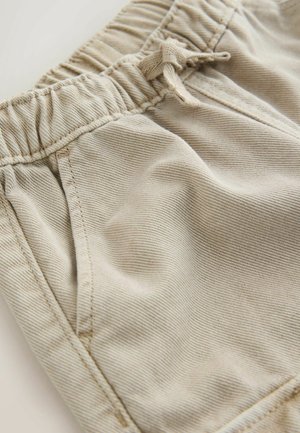 Beige színű rövidnadrág rugalmas derékkal, húzózsinórral és oldalsó zsebekkel. Texturált anyagból készült, finom függőleges csíkokkal.