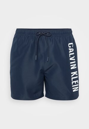 Marineblaue Badeshorts mit elastischem Bund und Kordelzug. Mit vertikal auf der Seite aufgedrucktem weißen "CALVIN KLEIN"-Markenzeichen. Glatte Textur.