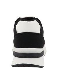 Chaussure de sport blanche et noire vue de dos avec une semelle blanche épaisse et une semelle extérieure noire.