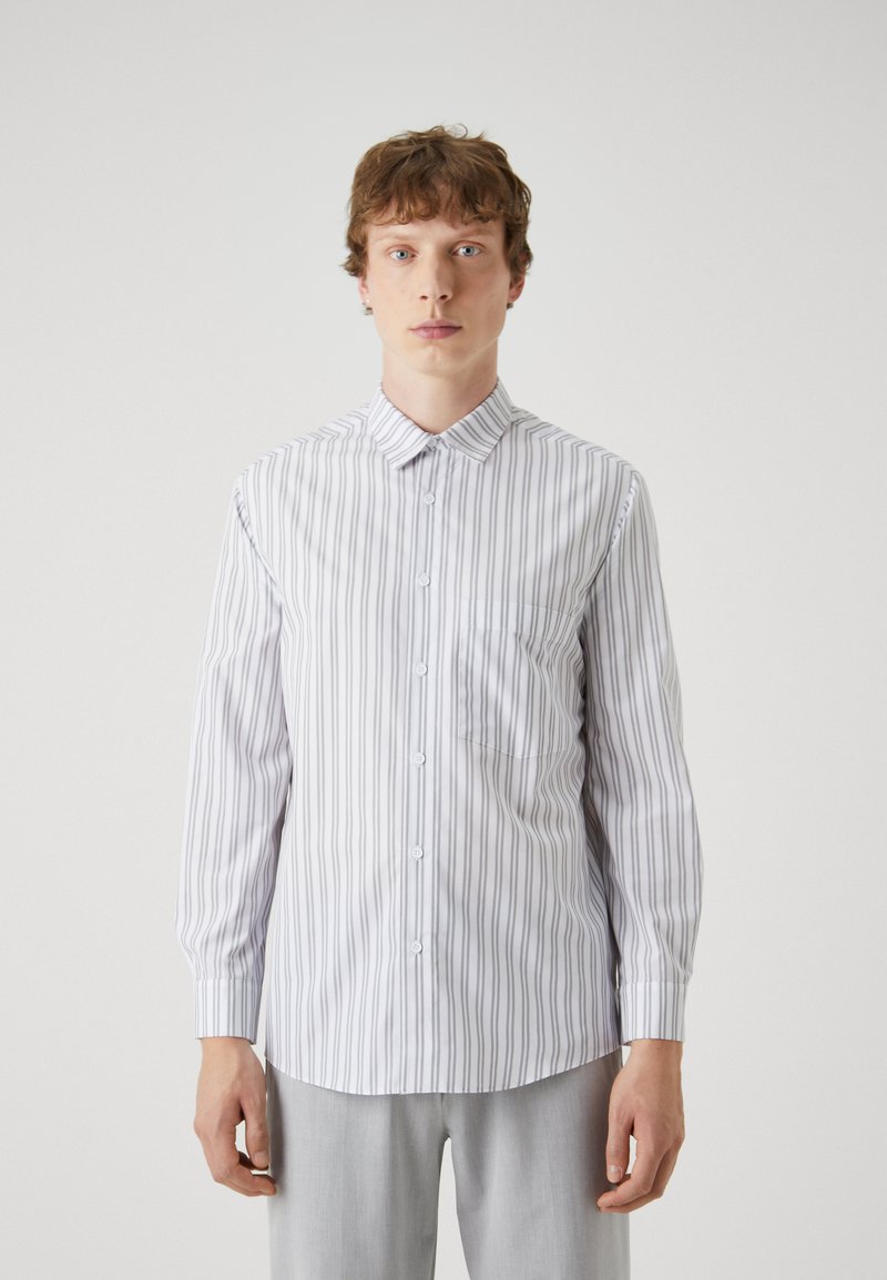 White shirt with vertical gray stripes, button-up design, pointed collar, long sleeves, and left chest pocket. Smooth texture, tailored fit.