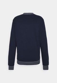 Felpa blu navy con dettagli a righe bianche sul colletto e sui polsini, caratterizzata da un design semplice e privo di decorazioni, e una texture morbida.