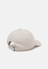 Căciulă de baseball din bumbac bej, cu coroana rotundă, vizor curbat și cataramă metalică ajustabilă în spate. Prezintă șase orificii de ventilație.