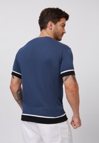 Heren blauwe t-shirt met korte mouwen, voorzien van witte en zwarte details op de mouwen en rand, gemaakt van een zachte stof, met een aansluitend ontwerp.