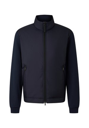 Marineblauw jack met een gewatteerde voorkant, contrasterende gebreide mouwen, hoge kraag en ritssluitingen aan beide zijden. Overal een gladde textuur.