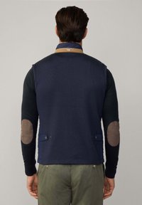 Gilet tricoté marine avec un col beige, doté de coudières, de deux poches latérales et d'un dos texturé. Coupe ajustée.
