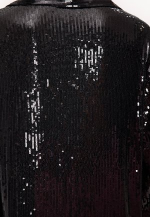 Tissu en sequins noirs avec une finition brillante, présentant une surface texturée couverte de petits disques réfléchissants disposés de manière rapprochée.