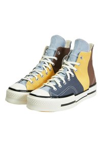 Höga sneakers i en blandning av gul, blå, brun och grå canvas. Vita skosnören, gummisula och svarta detaljer på botten.