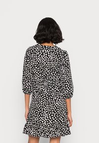 Vestido preto com padrão de pinceladas brancas, mangas bufantes, cintura ajustada e barra rodada, feito de um tecido leve.