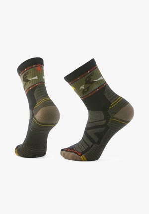 Kniestrümpfe in Khaki und Dunkelgrün mit geometrischem Muster, verstärkter Ferse und Spitze sowie roten und gelben Akzentstreifen.