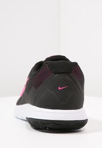 Černá sportovní bota s síťovinovým svrškem, růžovými akcenty, polstrovanou patou a bílou mezipodešví. Obsahuje texturovanou podrážku pro lepší trakci.